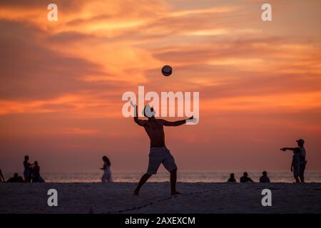 Persone che giocano a pallavolo sulla spiaggia durante il tramonto Foto Stock