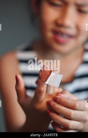 La ragazza prima ferita del dito di aiuto da se stessa Foto Stock