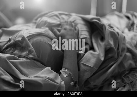 donna incinta con iv in mano in ospedale. Preparazione della manodopera e della consegna. Infusione di terapia intravenosa. Profondità di campo bassa. Fuoco selettivo Foto Stock