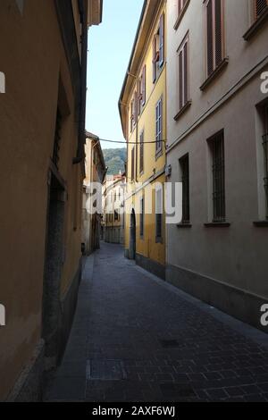 Guardando lungo la stretta e tortuoso Via Giuseppe Rovelli, case, luce del sole che cade su un palazzo, pomeriggio nel centro storico, Como, Lombardia Italia, Foto Stock