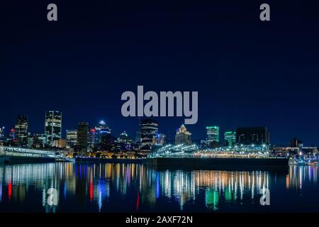 Splendido skyline notturno del porto di Dieppe Park con riflessi di luce colorati sul fiume Foto Stock