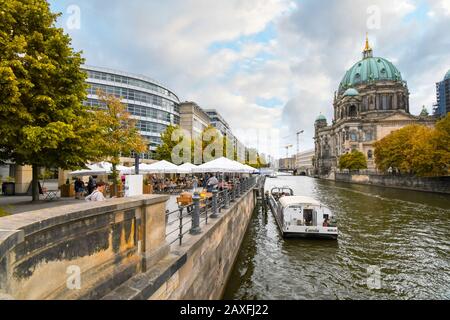 I turisti potranno godersi un pomeriggio d'autunno in un caffè sul lungomare lungo il fiume Sprea con vista sulla Cattedrale di Berlino. Foto Stock