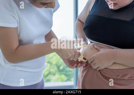 Giovane addestratore femminile che misura lo strato grasso di donna di peso eccessivo con il calibro a idoneità Foto Stock