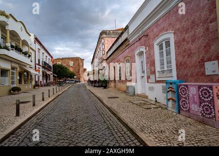 Silves, Portogallo - 23 gennaio 2020: Belle strade acciottolate con piastrelle rosa sugli edifici nel piccolo villaggio in Algarve Foto Stock