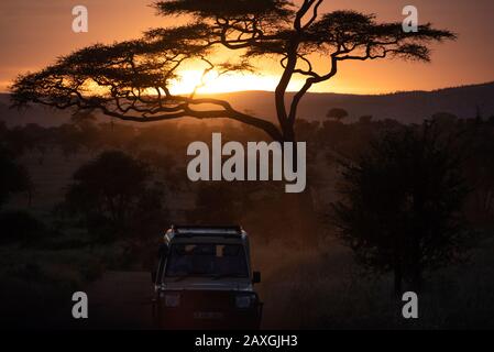 Tramonto con veicolo safari. Rientrati al campo dopo una lunga giornata fuori. Parco Nazionale Serengeti, Africa. Foto Stock