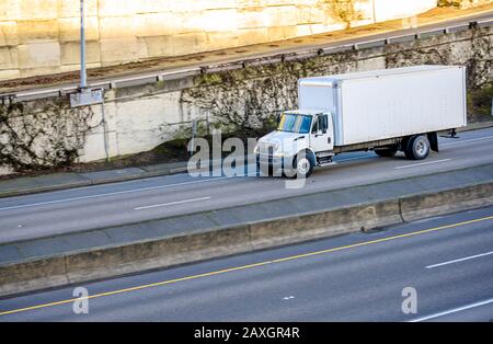 Carro di media portata semi-autocarro industriale bianco di dimensioni compatte per consegne locali che trasportano carichi commerciali per la consegna tempestiva in un rimorchio con furgone asciutto Foto Stock