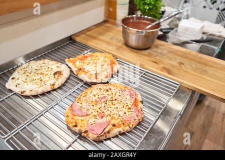Pizza napoletana con prosciutto iberico artigianale, pizza con prosciutto e salsiccia su tavola di legno, cucina Foto Stock