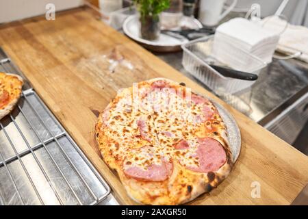 Pizza napoletana con prosciutto iberico artigianale, pizza con prosciutto e salsiccia su tavola di legno, cucina Foto Stock