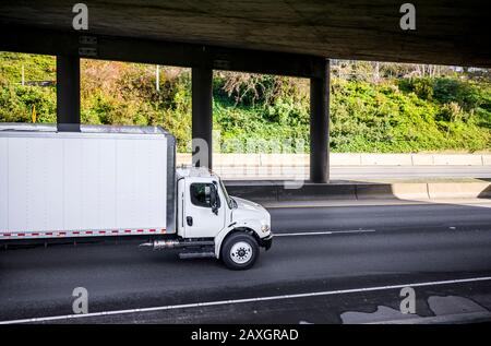 Carro di media portata semi-autocarro industriale bianco di dimensioni compatte per consegne locali che trasportano carichi commerciali per la consegna tempestiva in un rimorchio con furgone asciutto Foto Stock