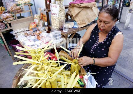 Antipolo City, Filippine - 11 febbraio 2020: Il venditore di marciapiedi vende riso Suman o gluteno al vapore in foglie di palma e altre specialità filippine Foto Stock