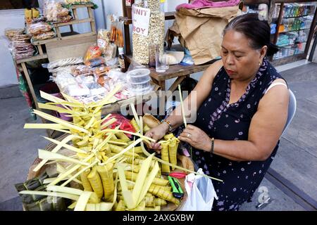 Antipolo City, Filippine - 11 febbraio 2020: Il venditore di marciapiedi vende riso Suman o gluteno al vapore in foglie di palma e altre specialità filippine Foto Stock