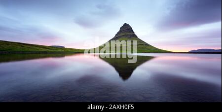 Paesaggio panoramico con la montagna di Kirkjufell, il lago limpido e il paesaggio cloudscape nel cielo soleggiato Foto Stock