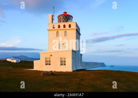 Splendido paesaggio con faro bianco a Cape Dyrholaey, situato sulla costa meridionale dell'oceano Atlantico in Islanda Foto Stock