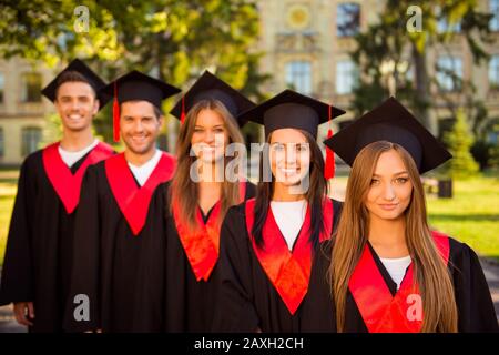 cinque laureati in abiti e cappelli con tasnel sorridente Foto Stock