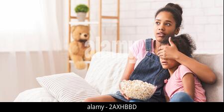 Scioccata ragazza africana teen che chiude gli occhi della sua sorella piccola Foto Stock