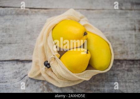 Mango in una borsa riutilizzabile su un'elegante superficie di una cucina in legno. Concetto di zero sprechi, concetto di plastica libera. Dieta sana e pulita e disintossicazione. Estate Foto Stock