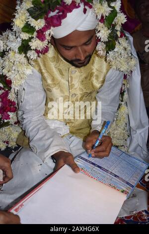 Lo sposo musulmano indiano che firma il nama di nikah o contratto di matrimonio un accordo prenuptial islamico ad Ahmedabad, Gujarat, India Foto Stock