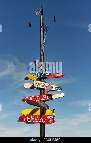 Cartello con cartelli direzionali colorati e distanze da diverse città Foto Stock