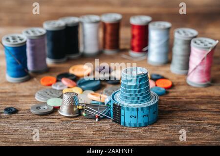 Gruppo di oggetti sulle apparecchiature per cucire impostato su uno sfondo di legno. Concetto di cucito e di sartoria Foto Stock