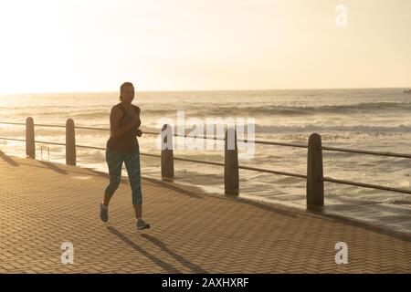 Vista frontale di una donna caucasica matura di mezza età che lavora su una passeggiata in una giornata di sole al tramonto, in esecuzione Foto Stock