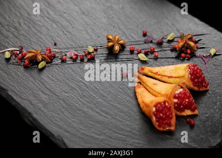 Pate di coniglio in corni croccanti decorato con spezie su un piatto di pietra nera Foto Stock