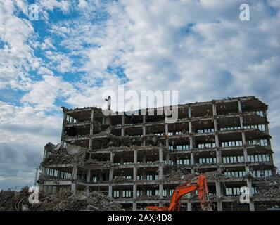 Un edificio completamente eviscerato per uffici viene demolito con l'escavatore Foto Stock