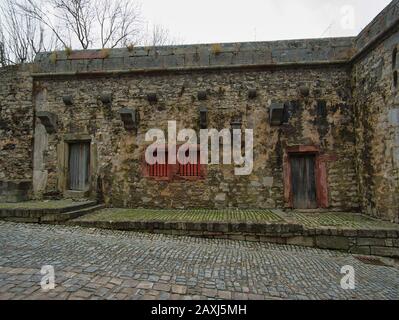 Una vecchia casa in pietra con finestre e porte integrate in un muro di fortezza Foto Stock