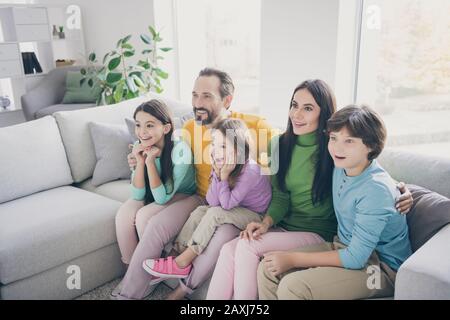 Eccitato pazzo energico famiglia papà papà mamma mamma mamma tre bambini piccoli pre scolaretto scolaretto seduto divano guardare incredibile serie tv stupito Foto Stock