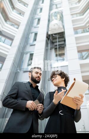 Sotto vista dei project manager che si trovano nella lobby d'ufficio ed esaminando la carta con preventivo Foto Stock