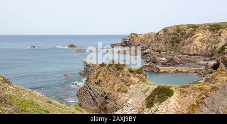 Coste rocciose frastagliate vicino al villaggio di Azenha do Mar, Alentejo Littoral, Portogallo, Europa meridionale Foto Stock