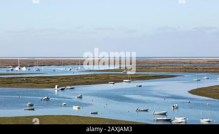 Paesaggio costiero di palude di sale con barche ormeggiate in meandering fiume canali di drenaggio lungo la costa al largo di Faro, Algarve, Portogallo Foto Stock