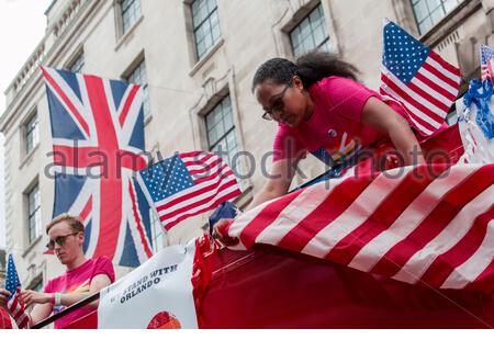 I partecipanti alla parata del London Pride fissano la bandiera degli Stati Uniti al lato di un autobus prima che la parata inizi Foto Stock