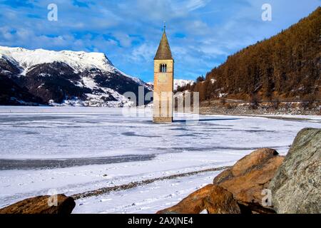 Paesaggio invernale nelle Alpi con la famosa torre della chiesa sommersa a Reschensee al confine tra l'Alto Adige e l'Austria Foto Stock