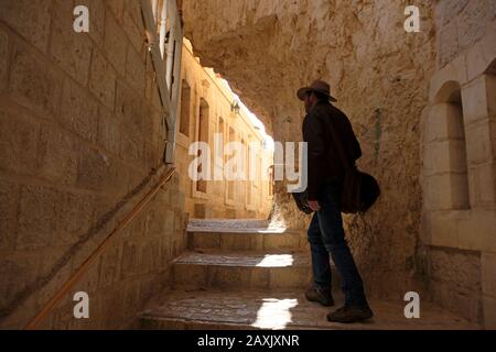 Una passeggiata turistica lungo uno stretto corridoio con camere su entrambi i lati presso il Monastero Sacro Greco Ortodosso del Monte Sarantarion o La Tentazione costruita sulle pendici del Monte Della Tentazione situato lungo una scogliera che domina la città di Gerico nei territori Palestinesi situati vicino al fiume Giordano in La Cisgiordania, Israele Foto Stock