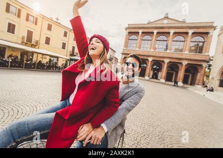 Felice giovane coppia innamorata di andare in bicicletta in un giorno d'autunno in città Foto Stock