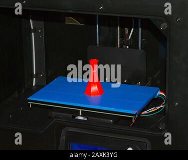 Stampante 3D stampa volume isolato triangolare oggetto colore rosso sulla base di sfondo blu e nero primo piano. Moderna tecnologia di stampa 3d Foto Stock