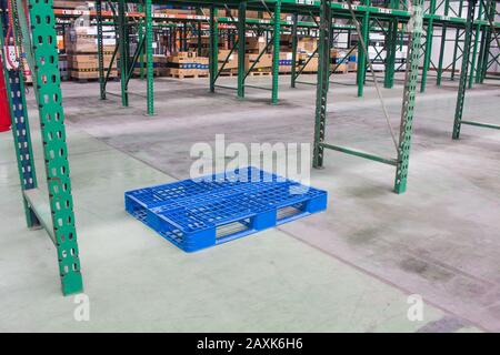 Pallet vuoti all'interno del magazzino con ripiani, pallet e scatole Foto Stock