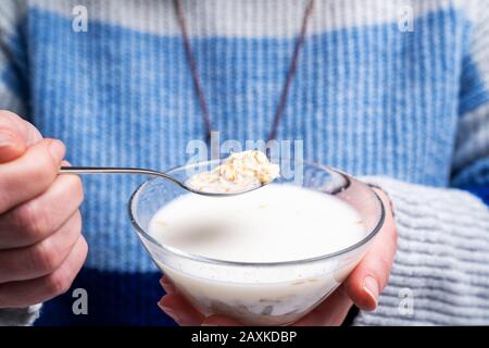 donna sta mangiando una ciotola di cereali laminati avena per colazione. Dieta e sano concetto di vita Foto Stock