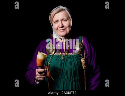 Studio ritratto di una donna bionda matura in costume vichingo, con un pallone e un corno per bere. Ritratto di un amante della storia vivente Foto Stock
