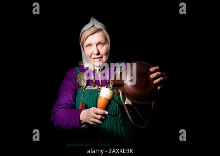 Studio ritratto di una donna bionda matura in costume vichingo, con un pallone e un corno per bere. Ritratto di un amante della storia vivente Foto Stock