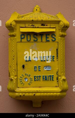 Vecchia letterbox giallo francese su un muro Foto Stock