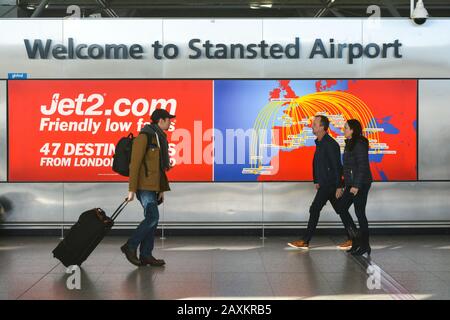 London Stansted Airport STN, Regno Unito, cartello di benvenuto all'ingresso Dei Viaggiatori Airoprt con i tram e i passeggeri a piedi. Brexit Foto Stock