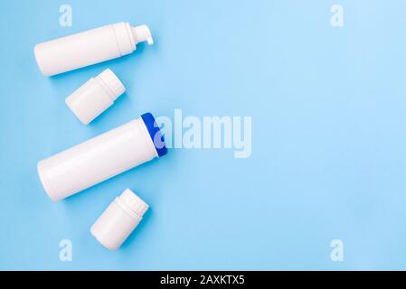 Set di prodotti cosmetici bianchi su sfondo azzurro. Un certo numero di contenitori per cosmetici. Cura del corpo femminile. Foto Stock