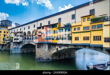 Il ponte dell'arco medievale in pietra di Ponte Vecchio, che attraversa l'Arno a Firenze, è fiancheggiato dai negozi di gioiellerie, commercianti d'arte e venditori di souvenir, Foto Stock