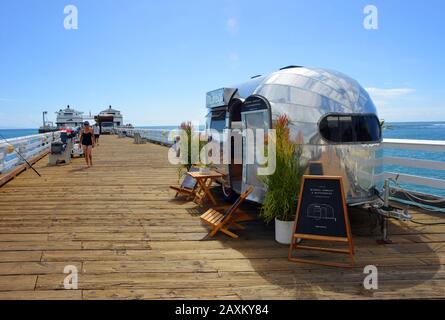 Malibu, USA 10-11-2018 Pier con canne da pesca e caravan negozio con cielo trasparente e sole persone a piedi Foto Stock