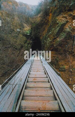 Scalinata che segue la grotta scavata. Antiche miniere in Ucraina. Un viaggiatore che scende verso gli antichi adits Foto Stock