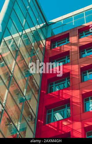 edificio alto e moderno in stile high-tech con pareti rosse, finestre quadrate e filtro di parte trasparente Foto Stock