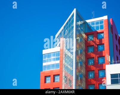 facciata di un edificio moderno nello stile di pareti rosse hi-tech, finestre quadrate in una giornata di sole con cielo blu chiaro. Spazio per il testo Foto Stock