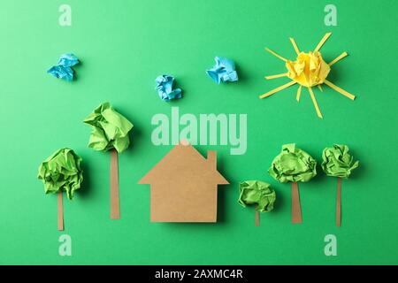 Casa di carta, nuvole, sole e alberi su sfondo verde, vista dall'alto Foto Stock