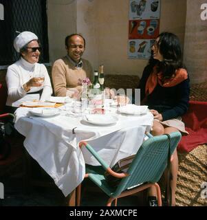 1960, storico, tre persone sedute "all'aperto" su un tavolo coperto di stoffa per pranzare al ristorante del Pescatore, Roma, Italia Foto Stock